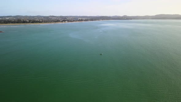 Flying alongside ocean kayaker In Orewa, New Zealand on summers day.