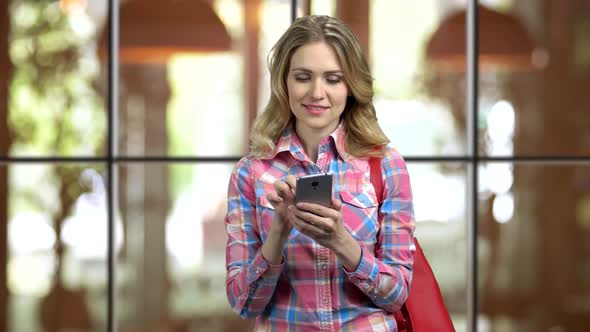 Young Girl in Casual Cloth and Purse Entartaining with Social Media on Phone