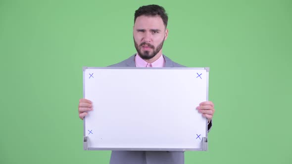 Stressed Young Bearded Businessman Holding White Board and Getting Bad News