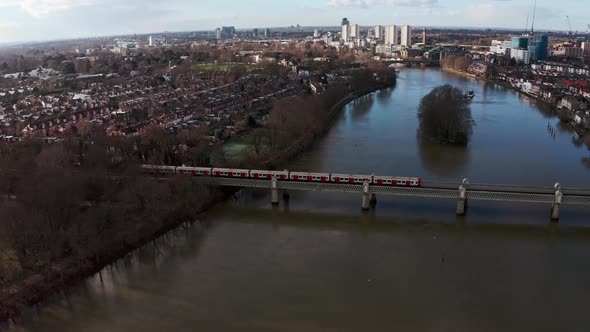 Cinematic rotating drone shot of London district line train on Kew railway bridge