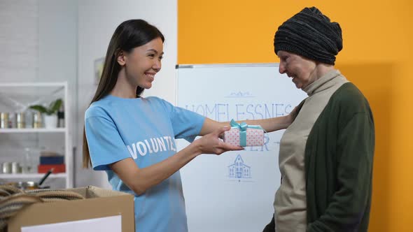 Smiling Volunteer Presenting Gift Box to Needy Aged Female, Philanthropy Care