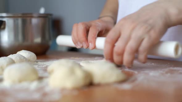 Woman Rolls the Dough with a Rolling Pin Shaping the Dough