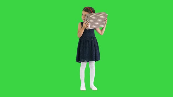 Happy Girl in Black Dress Shaking and Opening Gift Box Smiling at Camera on a Green Screen Chroma