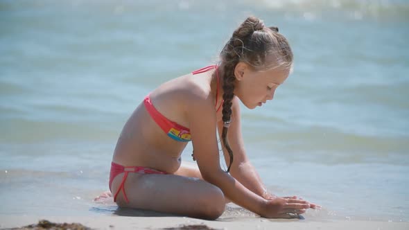 Girl Playing with Sand on the Beach