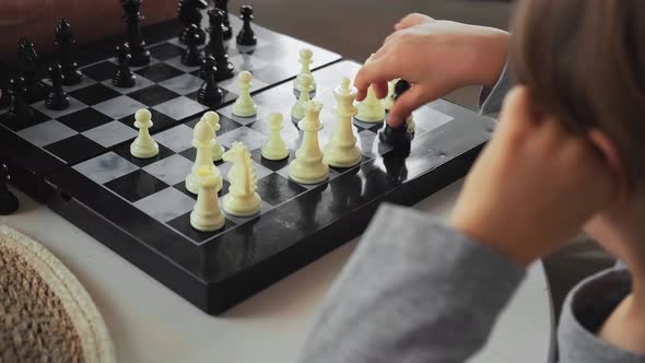 Senior Teacher Learning a 4 Year Old Child Playing Chess Sitting at the Table Close Up