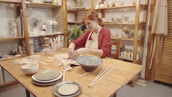 Happy Female Potter Making Handmade Earthenware Vessel in Workshop