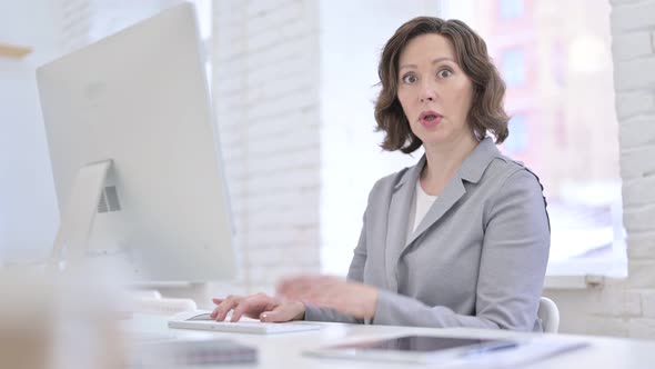 Creative Old Woman Get Surprise on Desktop and Looking at Camera