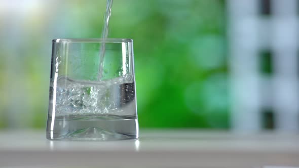 Closeup Pouring Purified Fresh Drink Water From the Bottle on Summer Background