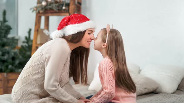 Happy Family Mother and Cute Daughter Smiling Playing Touching Nose Celebrating Christmas Holiday