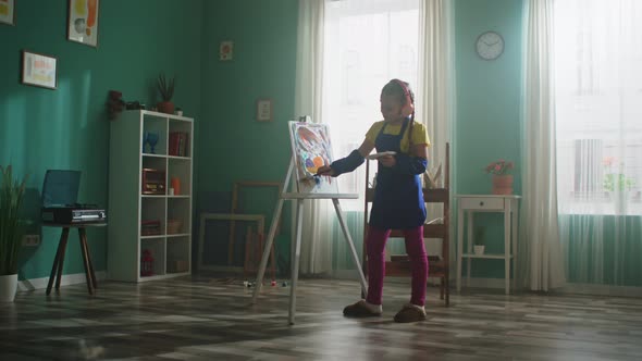 Small Girl In Apron Is Painting and Listen Music