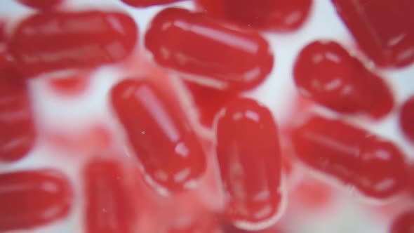 Red Capsules Of The Medication Is Falling Down Into The Camera