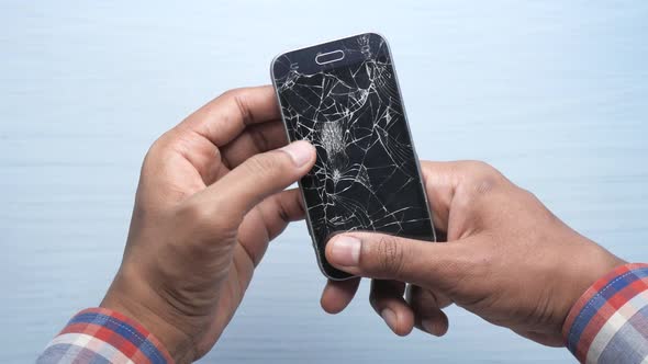 Close Up of Man Hand Holding Broken Smart Phone.