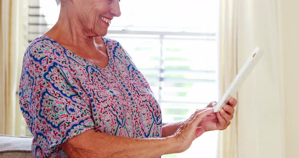 Senior woman using digital tablet in living room