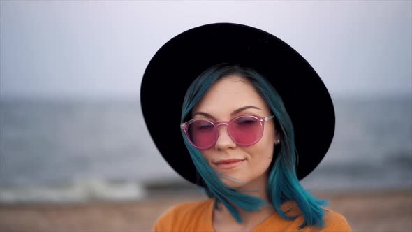 Portrait of Hipster Girl with Unique Fashionable Blue Hairstyle and Hat on Beach. Unusual Woman in