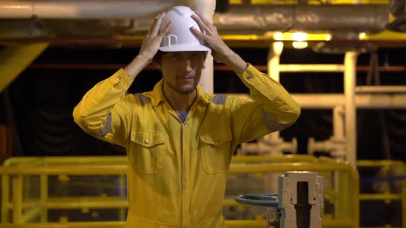 Young Man in a Yellow Work Uniform, Glasses and Helmet in Industrial Environment,oil Platform or