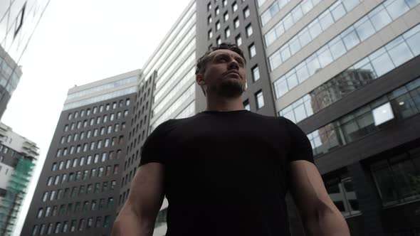 Young Man Stands Proudly Against the Background of a Modern Building