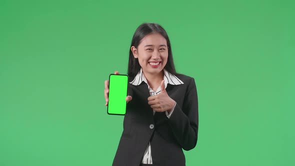 Asian Business Woman With A Smile Showing Green Screen Mobile Phone And  Thumbs Up On Green Screen