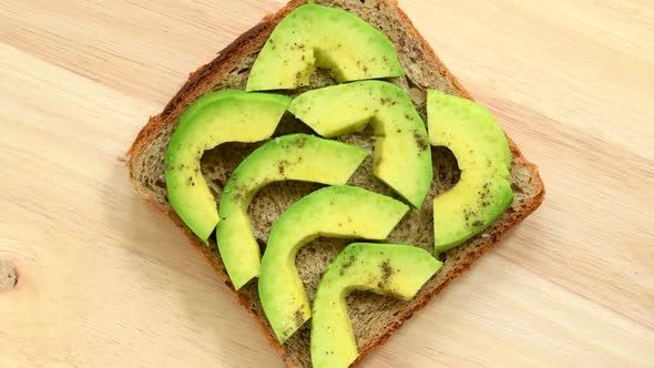 Sandwich with slices of avocado with pepper and salt top view