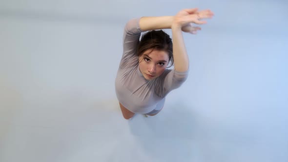 The girl dances a modern dance in a bright studio. Slow and smooth movement. View from above.