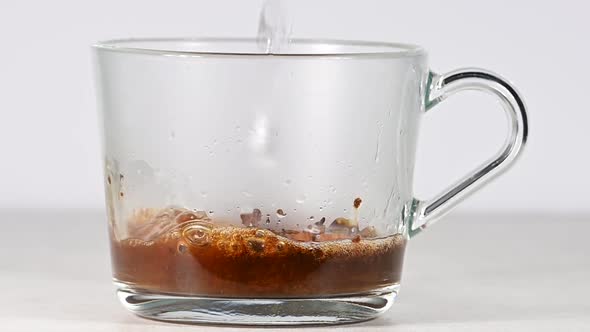 Pouring hot water in glass cup with coffee