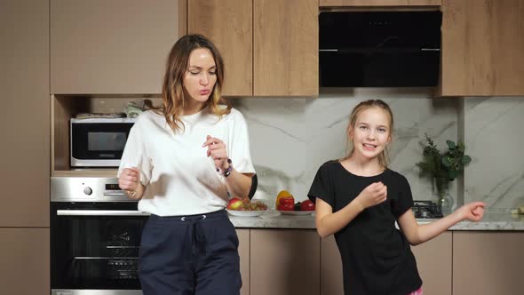 Mother and Teen Daughter Dance in Kitchen Premise at Home