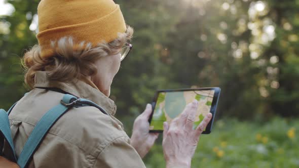 Senior Female Hiker Looking at Map on Tablet