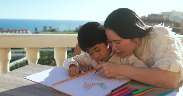 Asian mother and son doing homeworks together outdoor at home