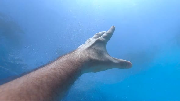 Male Hand Stretches From Under the Water to Sunrays