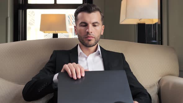Attractive Stylish Business Man Opening Laptop for Working at Luxury Hotel