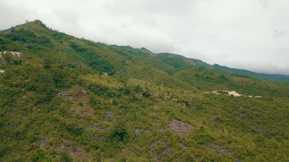 Beautiful aerial view tracking down the side of a forest-covered mountainside in central Cebu in the