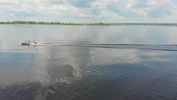 Two Men Riding Motor Boat on River - Green Islands on the Water