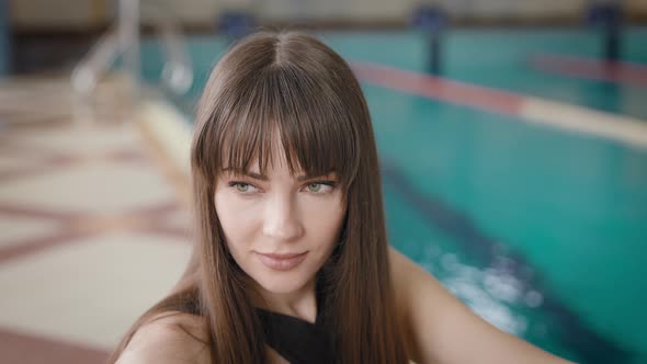 Portrait of a Beautiful Woman Against the Backdrop of a Large Pool