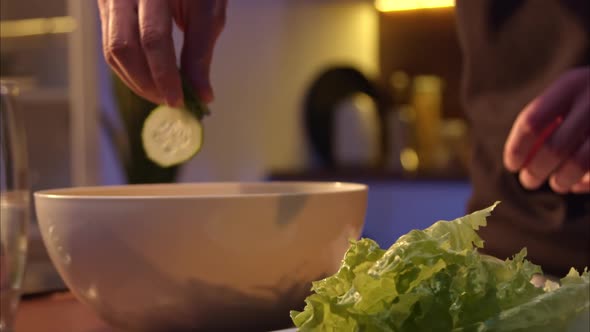 Men's Hands Throw Sliced Fresh Cucumbers Into a Salad