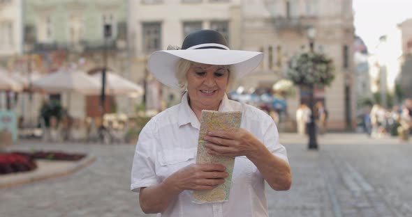 Senior Female Tourist Exploring Town with a Map in Hands. Looking for the Route