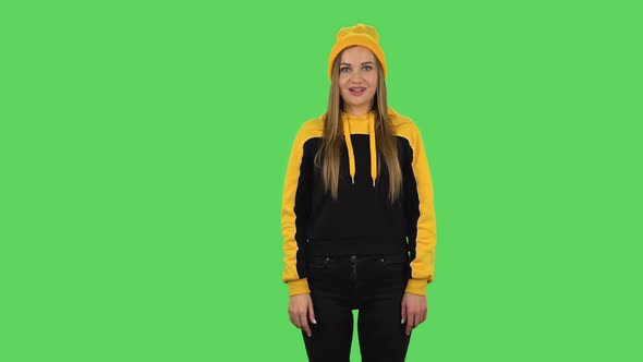 Modern Girl in Yellow Hat Is Smiling and Showing Heart with Fingers Then Blowing Kiss. Green Screen
