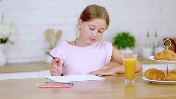 Girl Draws While Sitting in the Kitchen