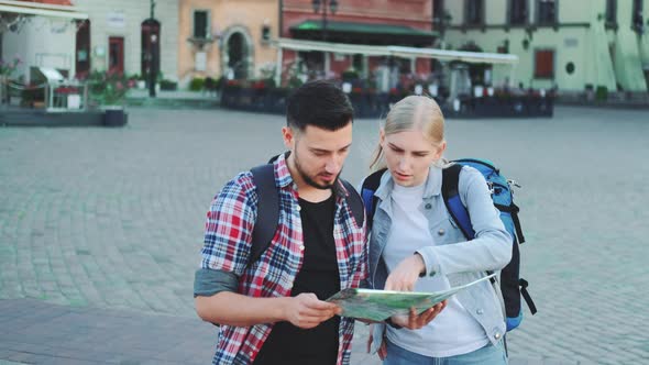 Couple of Tourists Holding Map and Looking for Some Place on City Square