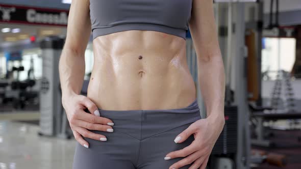 Confident young athletic woman with sixpack abs posing