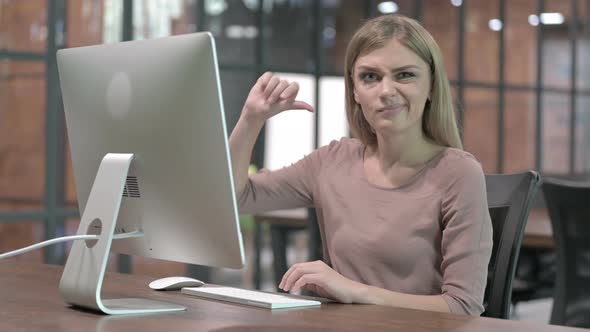 Young Woman Showing Thumbs Down While Working on Computer