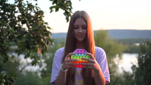 A Girl with Long Hair Plays Popit in Nature