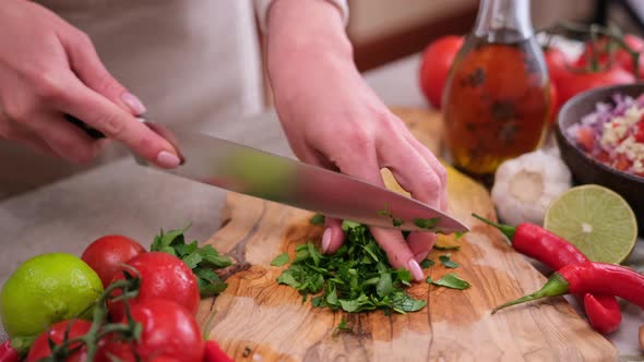 Woman Cutting and Chopping Cilantro or Parsley Greens on a Wooden Board
