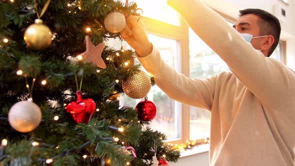 Man in Mask Decorating Christmas Tree at Home
