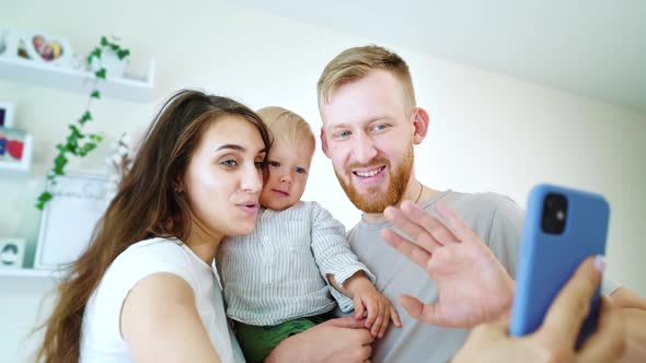 Happy family with baby video calling relatives using smartphone