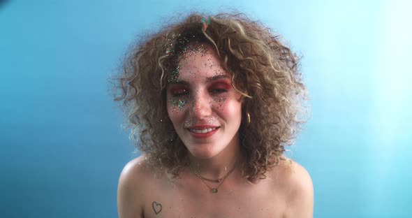 Curly girl smiling and looking at the camera with her face full of glitter