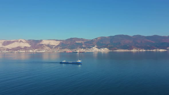 Aerial View of Large Cargo Ship Leaving Sea Harbour at Sunny Day