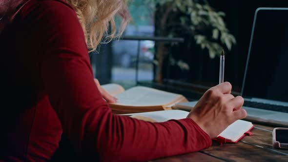 A Young Sad Female Student Overwhelmed with Homework Sits with a Laptop in a Cafe alt