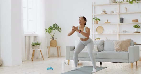 Young African American Woman Practicing Deep Squats Exercise at Home Interior, Slow Motion