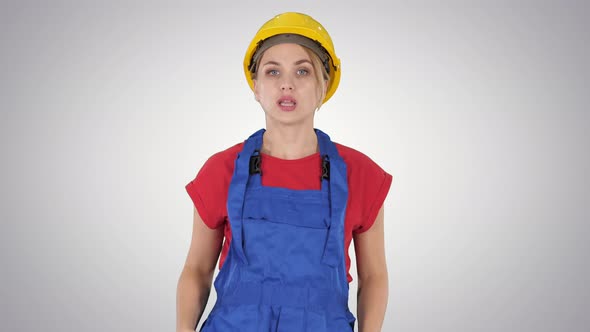 Woman in Construction Outfit Talking To Camera While Walking on Gradient Background