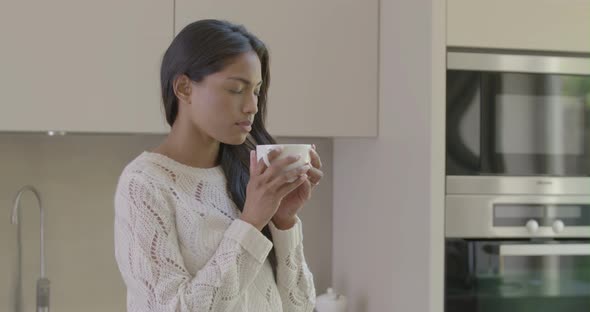 Woman smelling and drinking coffee in kitchen