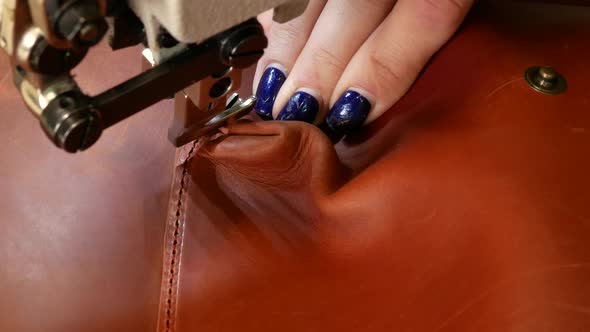 A Seamstress Sews a Pocket To a Leather Backpack in a Sewing Workshop. A Woman Operates Sewing